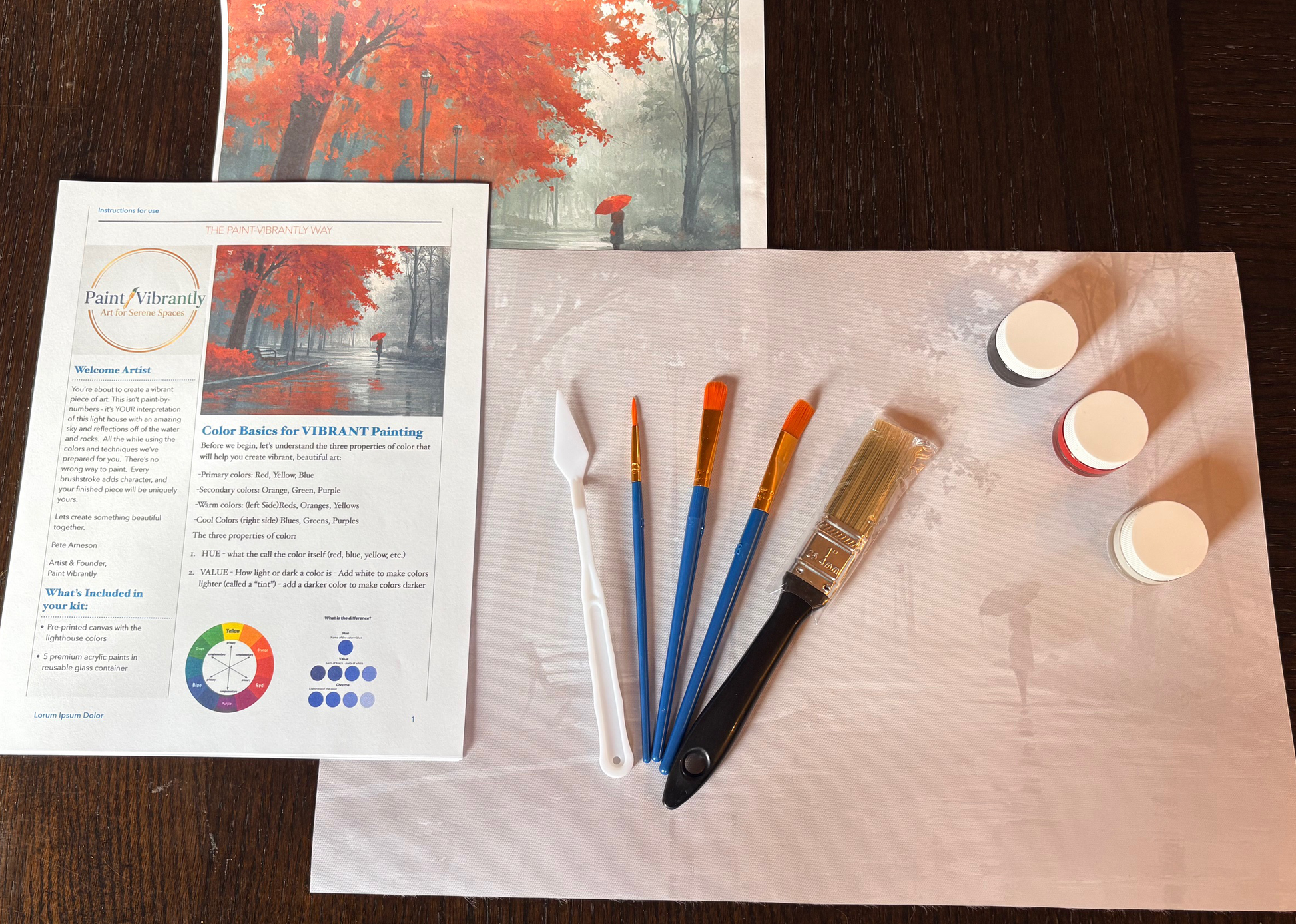 Painting supplies including brushes and a color chart on a wooden surface.
